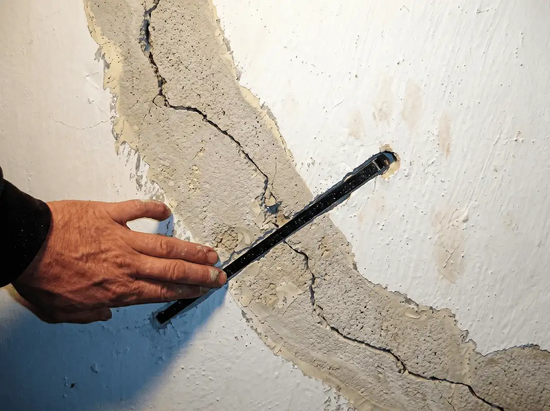 A wall with a large crack is being inspected by a professional in Chandler, AZ